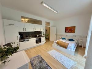 a white bedroom with a bed and a kitchen at Giardino Airport Apartment with garden in Schwechat