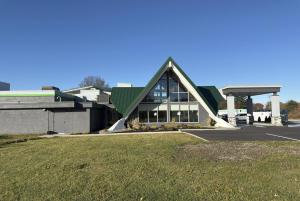 a large building with a green roof and a parking lot at Wingate by Wyndham Geneva at SPIRE Academy in Geneva