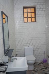 a bathroom with a toilet and a sink and a mirror at Off Airport Kilimanjaro lodge in Boma la Ngombe
