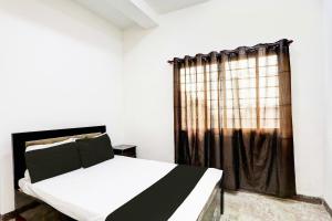 une chambre avec un lit noir et blanc et une fenêtre dans l'établissement Hotel O Raj Mahal, à Jabalpur