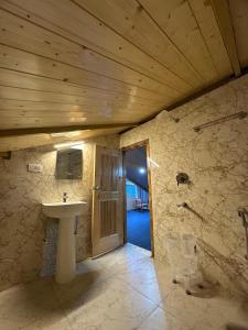 a bathroom with a sink and a wooden ceiling at Yellow Stone Cottage and Cafe in Jibhi