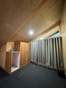 a room with wooden walls and curtains in a attic at The Woodpecker Inn Jibhi in Jibhi +89 photos