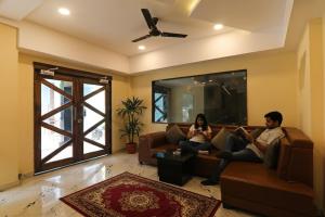 twee mensen zitten op een bank in een woonkamer bij FabHotel Blueark in Lucknow