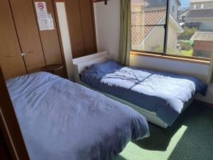 two beds in a room with a window at 合同会社ゲストハウス縁 in Saijo