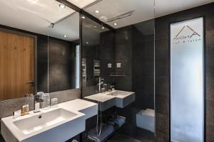 a bathroom with a sink, mirror, and bathtub at Anova Hotel & Spa in Montgenèvre