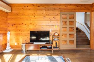 a living room with wooden walls and a flat screen tv at Kugenuma Kaigan Beachside House#ENOSHIMA#Aquarium in Fujisawa