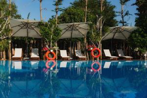 a swimming pool with umbrellas and lounge chairs and a swimming pool at NV Sport Camping & Hotel - Ho Tram in Xuyên Mộc