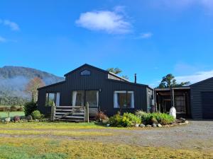 a black house with a fence in front of it at Waimanu Guest House in Franz Josef