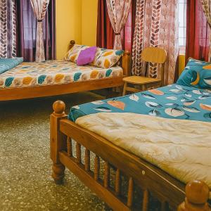 a bedroom with two beds and a chair at Pushpa Nilaya in Madikeri