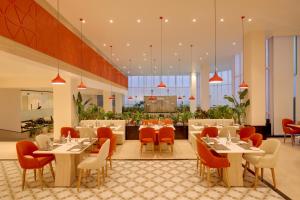 a restaurant with white tables and red chairs at Lemon Tree Hotel, Ranchi in Rānchī