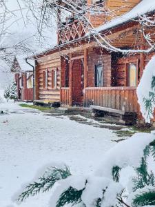 Cabaña de madera en la nieve con porche en «У полоні гір», en Verkhovyna