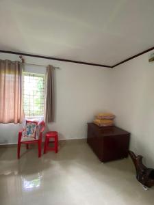 - un salon avec une chaise rouge et une fenêtre dans l'établissement Coorg jungle Cottage, à Kushalanagar