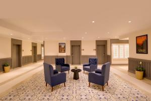 a waiting room with blue chairs and a rug at Lemon Tree Hotel, Ranchi in Rānchī