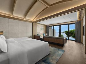 una camera da letto con un grande letto bianco e una grande finestra di 珠海凤凰湾悦榕庄 a Zhuhai Altre 44 foto