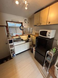 eine Küche mit einem schwarzen Kühlschrank und einer Mikrowelle in der Unterkunft サンハウス六本松103 in Susakiuramachi + 2 Fotos