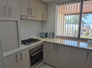 una cucina con mobili bianchi e un forno a piano cottura di Serenity by the Sea a Mandurah