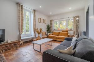 ein Wohnzimmer mit Sofa und Tisch in der Unterkunft La meulière de Guerlande - Disney 20min in Lumigny