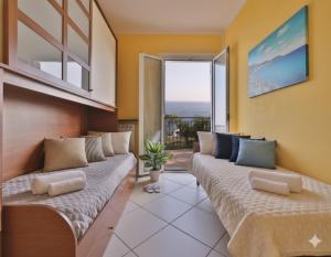 a living room with two beds and a window at Casa Conca Azzurra in Costarainera +8 photos