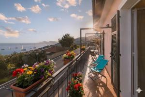 a balcony with flowers and chairs and a view of the ocean at Casa Conca Azzurra in Costarainera