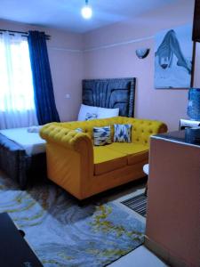a living room with a yellow couch and a bed at Guestroom in Malindi