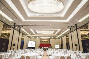 een feestzaal met witte tafels en stoelen en een kroonluchter bij The Margo Hotel in Depok