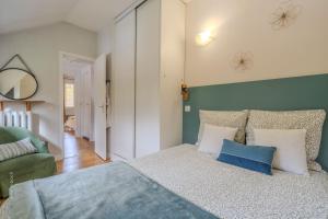 ein Schlafzimmer mit einem Bett mit blauen und weißen Kissen in der Unterkunft La meulière de Guerlande - Disney 20min in Lumigny