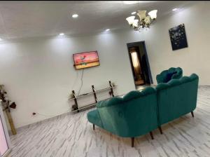 una sala de estar con un sofá verde y una pintura en MC Home, en Yaoundé