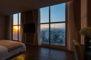 ein Hotelzimmer mit einem Bett und einem großen Fenster in der Unterkunft AMANA Hotel Phan Thiet in Phan Thiet
