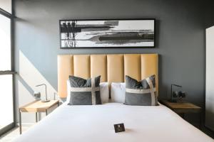 a bedroom with a large white bed with a large headboard at The Capital Mbombela in Nelspruit