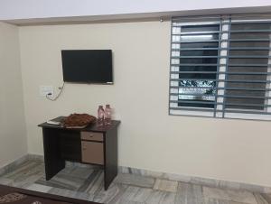 a room with a table with a tv on the wall at Msquare guest room in Godāvari