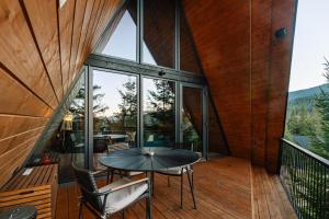 a glass house on a deck with a table and chairs at УЛІС Ворохта in Vorokhta