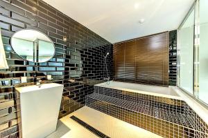 een badkamer met zwarte tegels, een bad en een spiegel bij Nine Boutique Hotel in Seogwipo +122 foto's