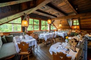een restaurant met witte tafels, stoelen en ramen bij Trattlers Hof-Chalets in Bad Kleinkirchheim