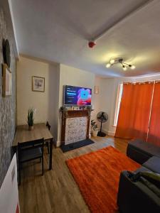 ロンドンにあるSky homesのテレビ、ソファ、テーブルのあるリビングルーム