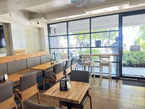 a restaurant with wooden tables and chairs and large windows at Ripple Beach Inn in Hulhumale