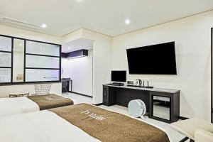 a bedroom with two beds and a flat screen tv at Hoteld Benikea in Osan