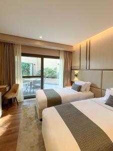 une chambre d'hôtel avec deux lits et un balcon dans l'établissement The Lake Hotel Tagaytay, à Tagaytay