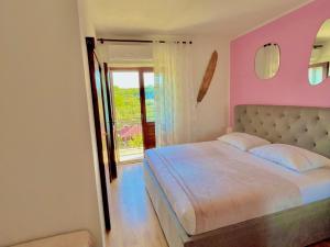 a bedroom with a bed with a pink wall at Villa Last Chance, Brač in Povlja