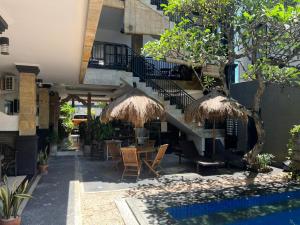 eine Terrasse mit einem Tisch, Stühlen und einer Treppe in der Unterkunft Tendan Residence Hotel in Legian