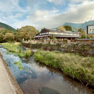 a building next to a river in front of a building at Shiki Art Hotel Yufu in Yufu