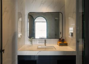 a bathroom with a sink and a mirror at AMANA Hotel Phan Thiet in Ấp Bình Hưng