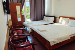 two beds in a room with two chairs and a window at Nhật Linh Homestay in Hue