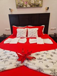 een bed met rode en witte dekens en kussens bij Ella Deluxe in Limenaria