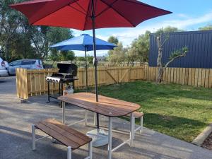 ein Picknicktisch mit Sonnenschirm und einem Klavier in der Unterkunft Nelson Road Apartment in Gisborne