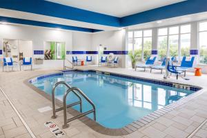 a swimming pool in a hotel room with blue chairs at Hilton Garden Inn Grand Forks-Und in Grand Forks