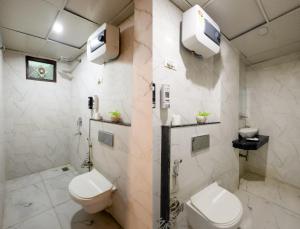a bathroom with two toilets and a tv on the wall at Hotel Tej Plaza FREE Airport Drop in New Delhi