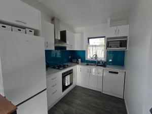 eine Küche mit weißen Schränken und blauen Wänden in der Unterkunft Nelson Road Apartment in Gisborne