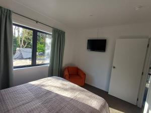 ein Schlafzimmer mit einem Bett, einem Fenster und einem Stuhl in der Unterkunft Nelson Road Apartment in Gisborne