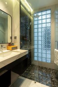a bathroom with a glass shower and a sink at AMANA Hotel Phan Thiet in Ấp Bình Hưng