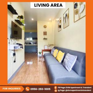 Una sala de estar con un sofá azul y una cocina. en DVM Apartment & Transient, en Manaoag